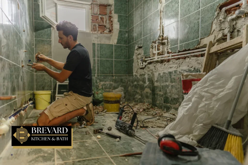 Contractor working on plumbing during a tub-to-shower conversion
